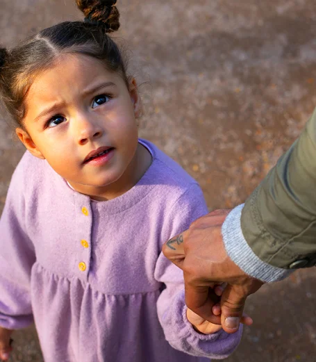 A child looking up to her parent or guardian